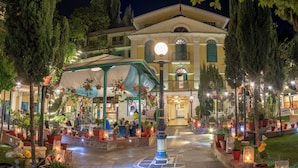 A well-lit courtyard with potted plants, a covered seating area, and a building with classical architecture. - Kathmandu Guest House by KGH Group (Kathmandu)
