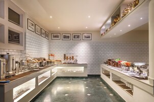 A modern hotel lobby with a long buffet table, white tiled walls, and framed pictures on the walls.
