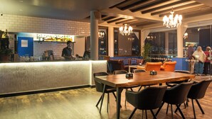 A restaurant with a bar area, wooden tables, and chairs. - Kathmandu Guest House by KGH Group (Kathmandu)