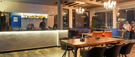 A restaurant with a bar area, wooden tables, and chairs.