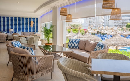 A spacious outdoor seating area with wicker furniture and a view of a pool area with umbrellas.