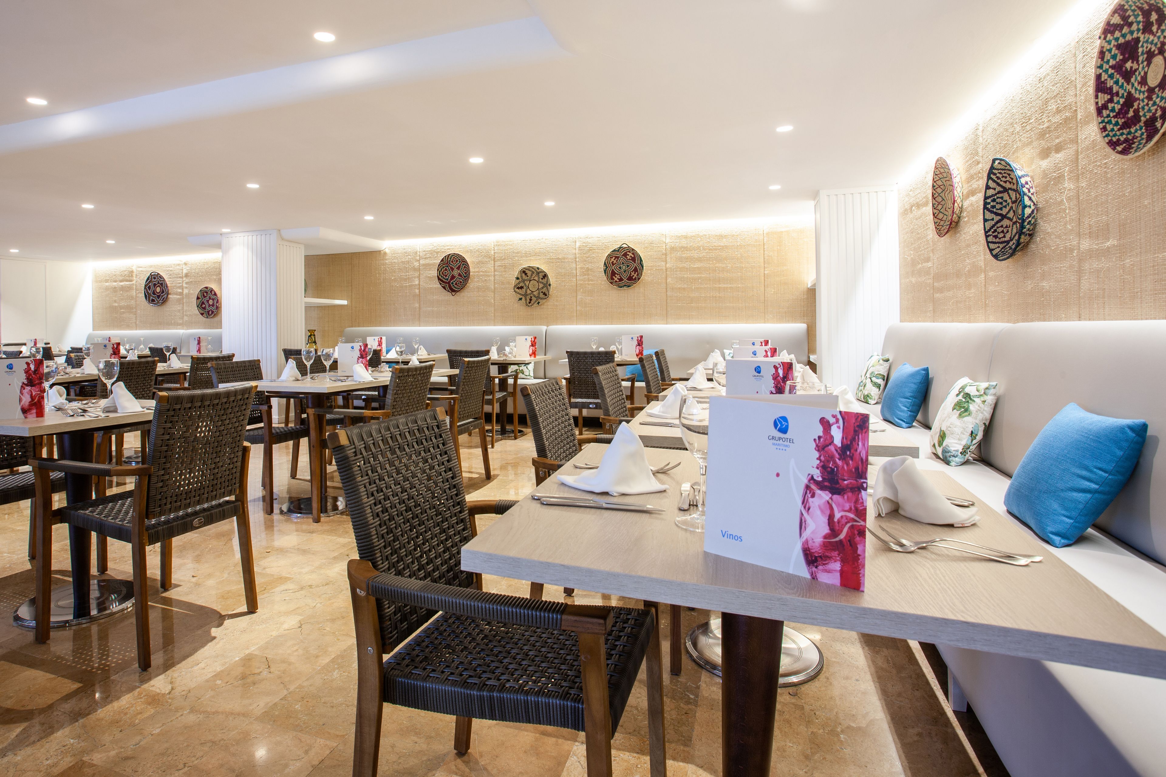 A restaurant with multiple tables and chairs, a sofa with cushions, and decorative wall art.