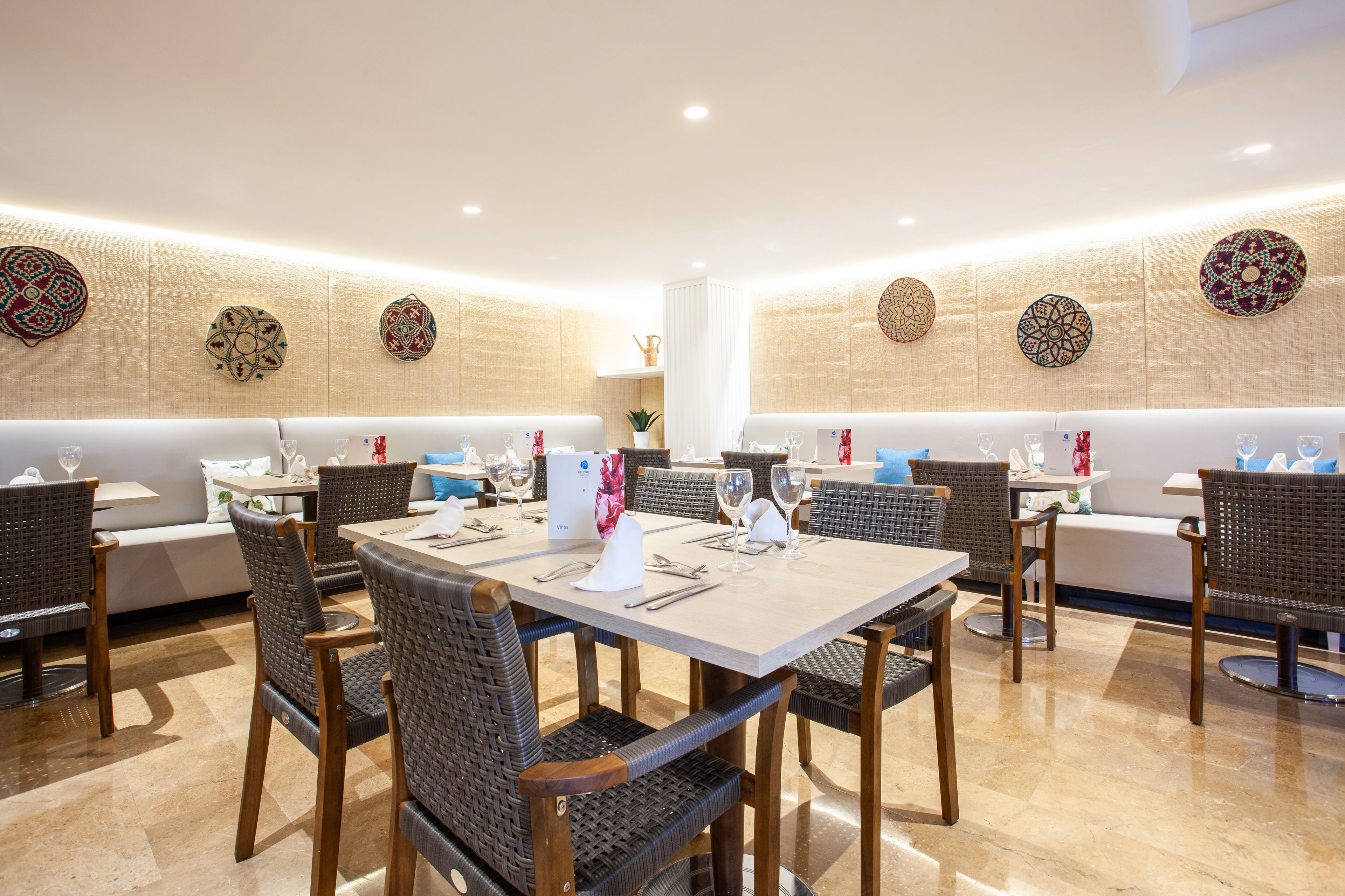 Zona pranzo con tavoli rotondi, sedie in vimini e decorazioni a parete.
