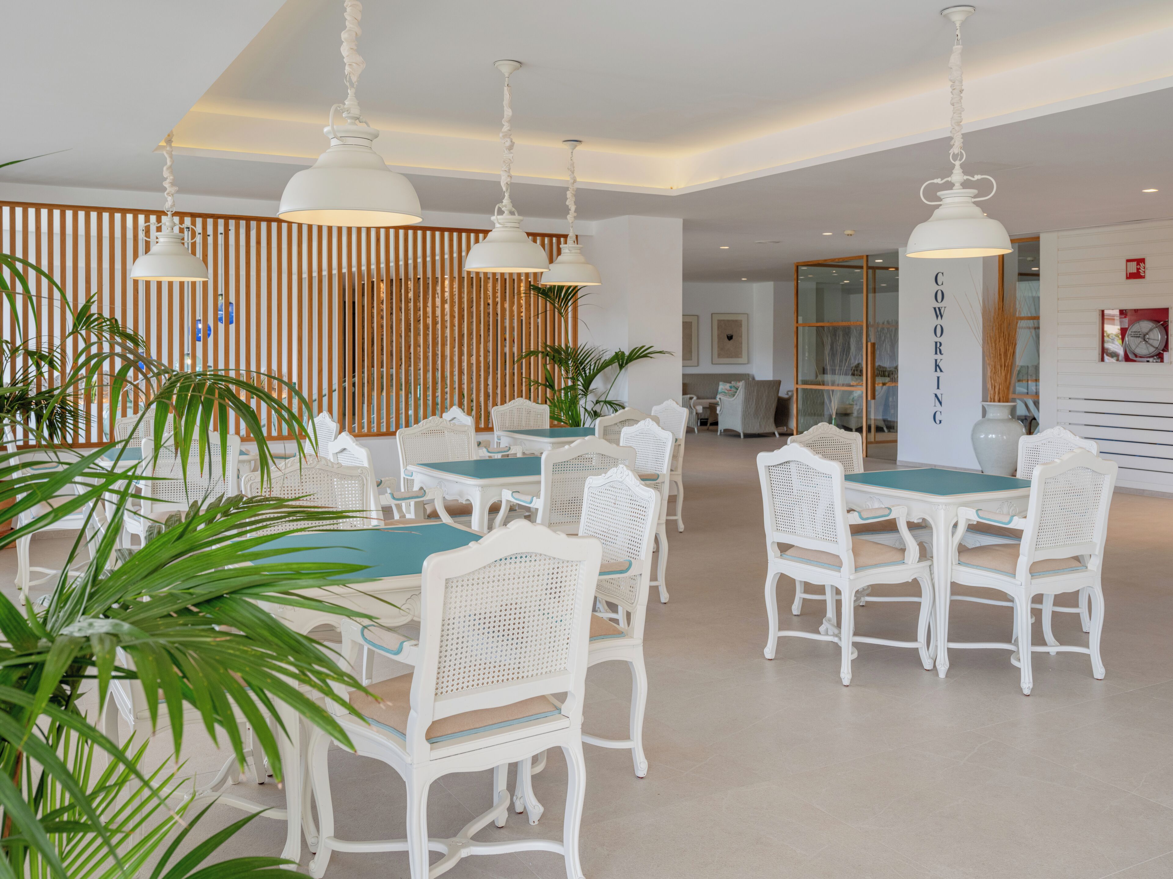 A modern dining area with white furniture and hanging pendant lights.
