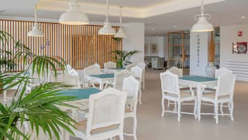 A modern dining area with white furniture and hanging pendant lights.