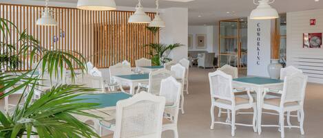 Un comedor moderno con mobiliario blanco y lámparas colgantes.