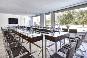 Une salle de conférence avec une longue table et des chaises, de grandes fenêtres et un téléviseur à écran plat.