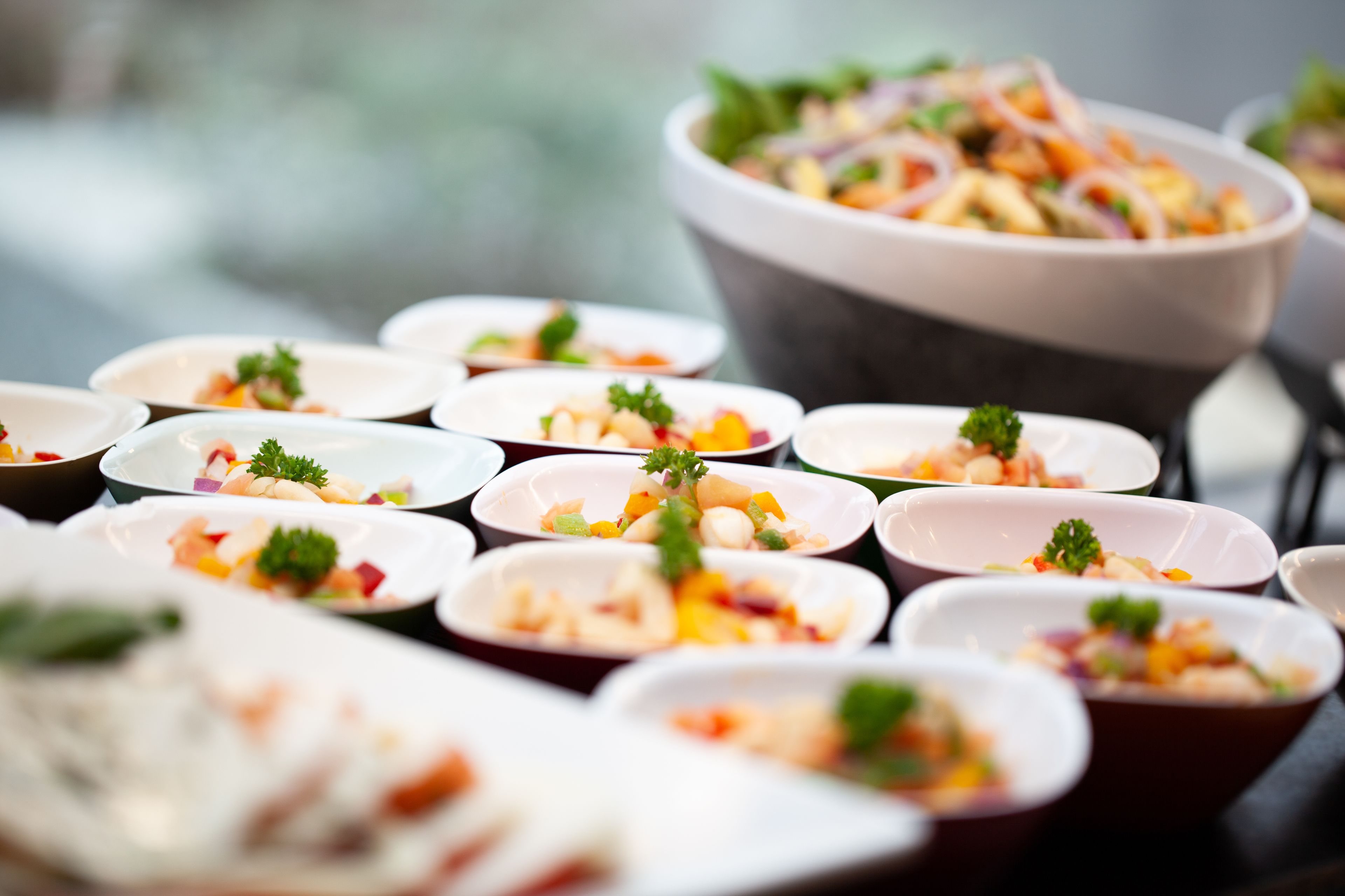 A variety of small bowls filled with colorful food items, likely appetizers, arranged on a table.