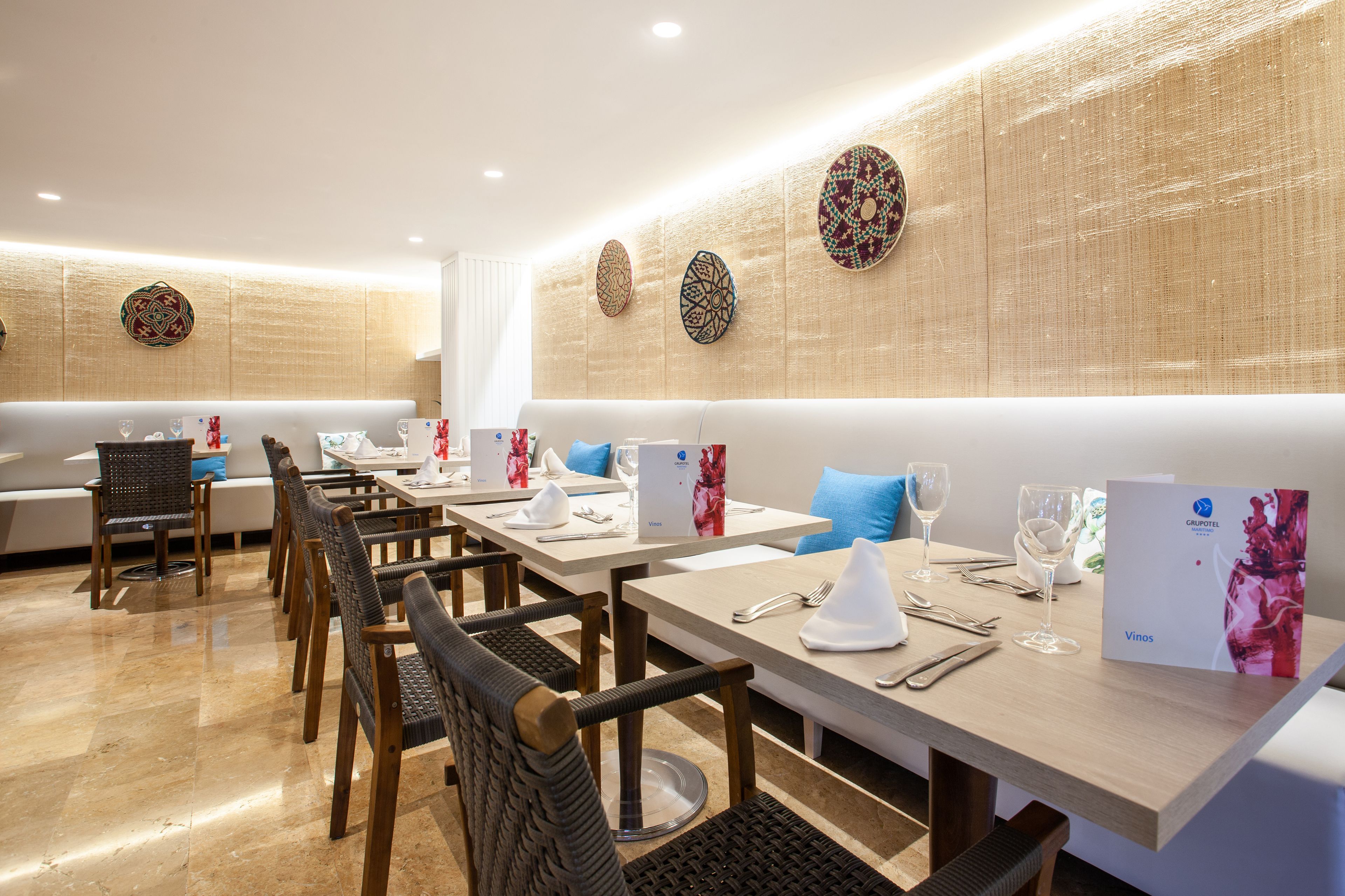 Un restaurant avec une longue table, des chaises et un mur décoré d’assiettes.
