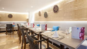 Un restaurant avec une longue table, des chaises et un mur décoré d’assiettes.