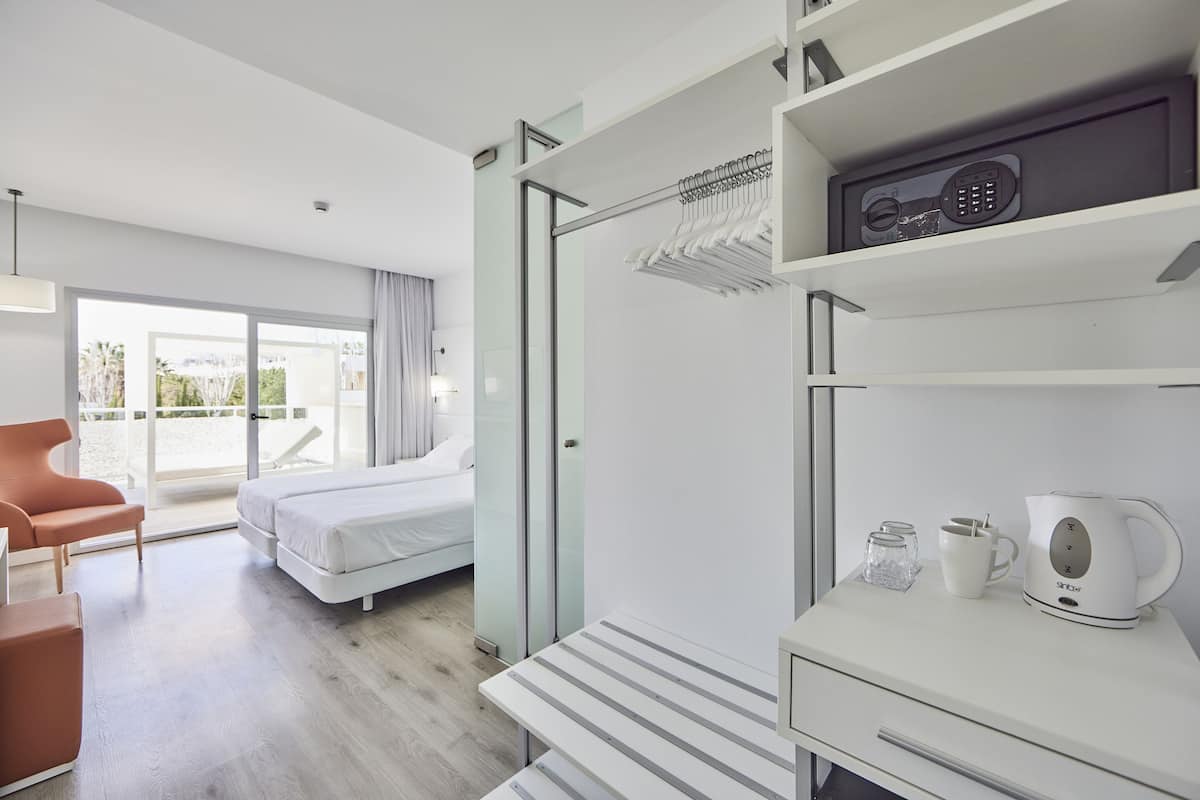 Une chambre d’hôtel moderne équipée d’un lit, d’un coin salon, d’une machine à café et offrant une vue sur l’extérieur.