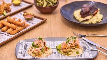 Ein Tisch mit verschiedenen Gerichten, darunter Tacos, Pommes und ein Steak.
