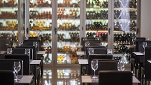L’intérieur d’un restaurant, avec des tables dressées pour le service, un présentoir à bouteilles en arrière-plan et un sapin de Noël.