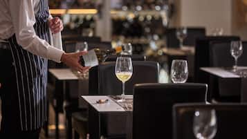 Iemand schenkt champagne in bij een glas op een restauranttafel.