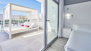 Une chambre à coucher moderne avec un grand lit, une porte vitrée donnant sur un balcon et une petite table de chevet.