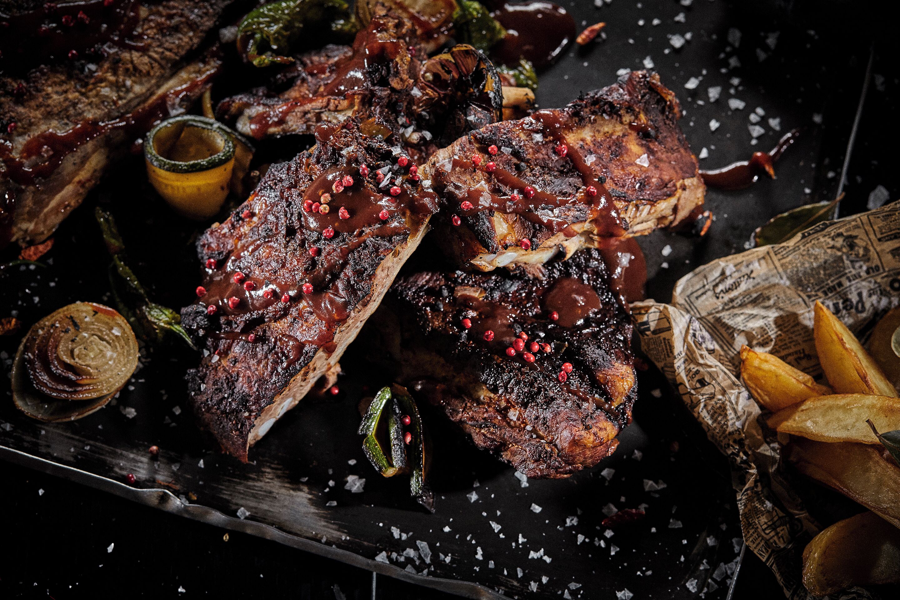 A steak with red peppercorns and a side of fries.