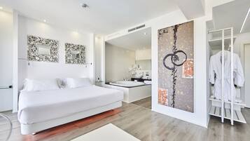 A modern bedroom with a large bed, a walk-in closet, and a bathroom with a bathtub.
