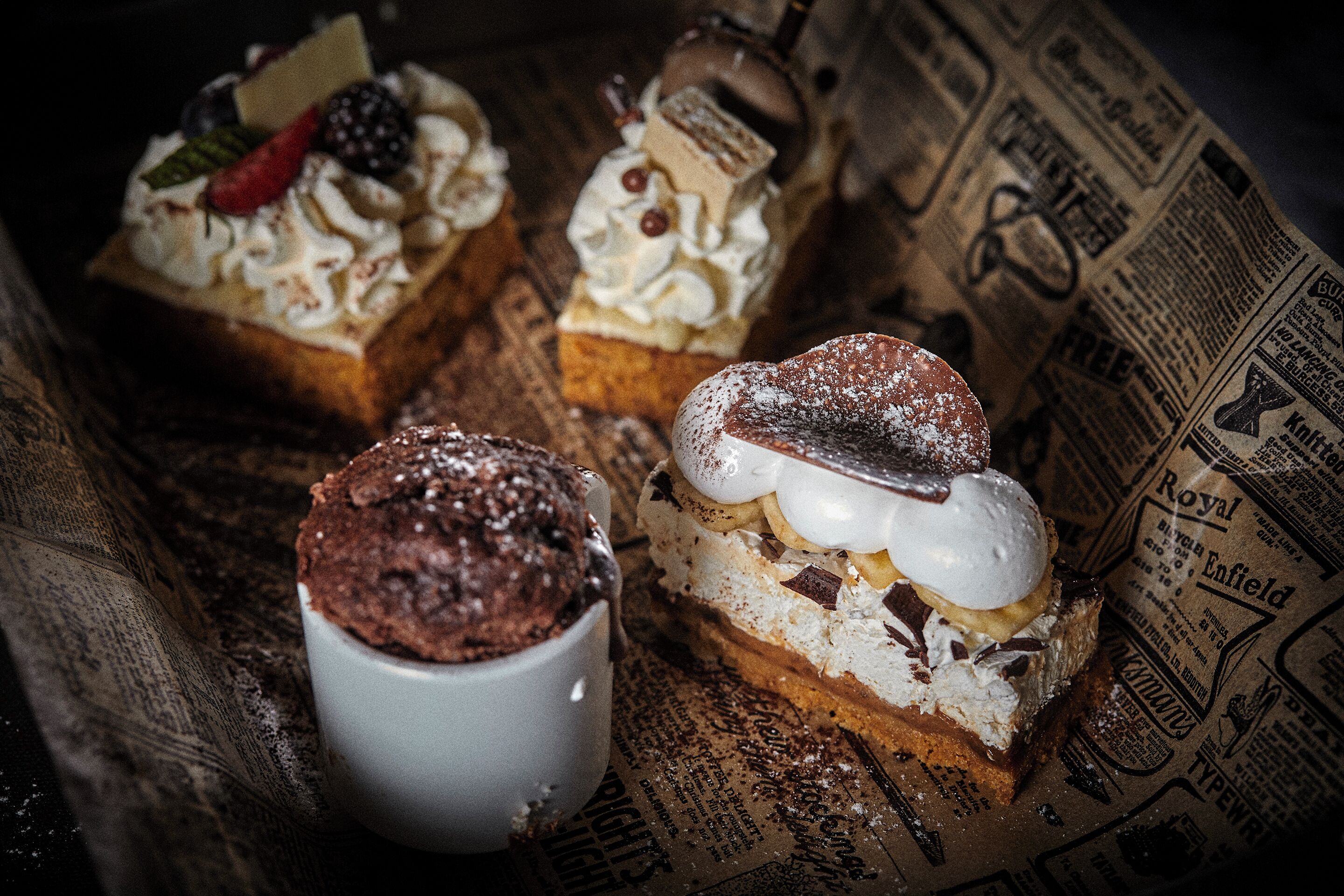 Three desserts on a table with a newspaper underneath.