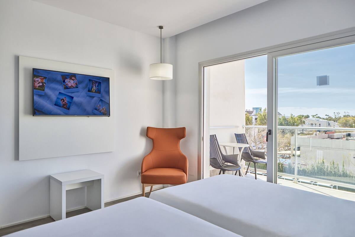 Une chambre d’hôtel moderne avec une grande fenêtre, un lit, une chaise et une petite table.