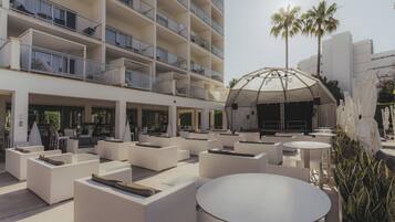 A hotel lobby with outdoor seating, a stage, and palm trees.