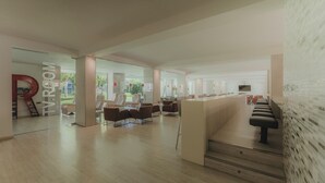 Un hall d’hôtel spacieux, doté d’un design moderne, comprenant un comptoir d’accueil, un espace salon et une salle de télévision.