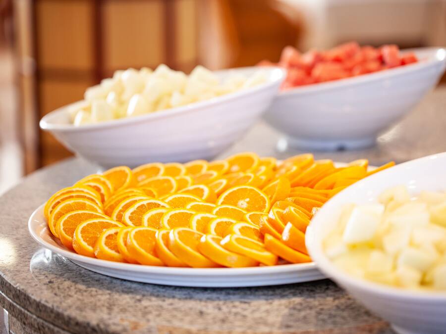A buffet table with various fruits including oranges, apples, and watermelon.