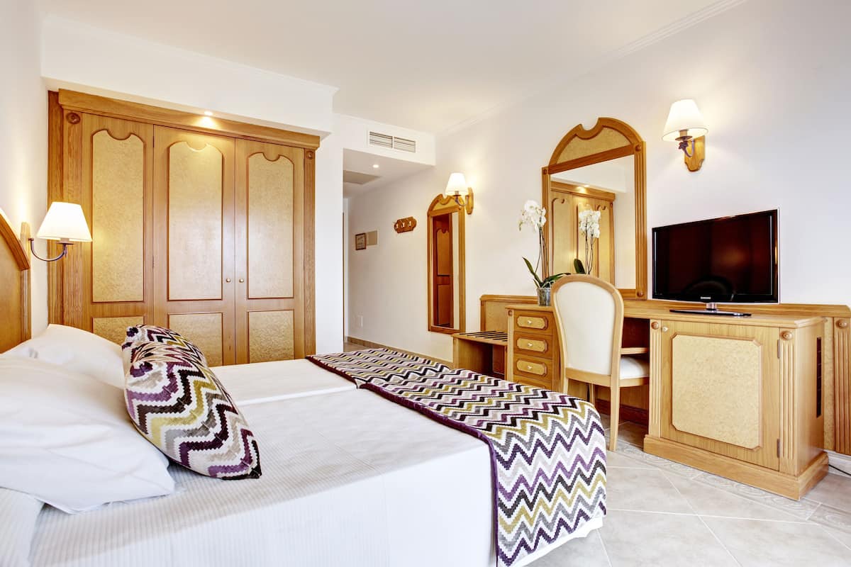 A hotel room with a bed, a desk, a television, and a wardrobe.