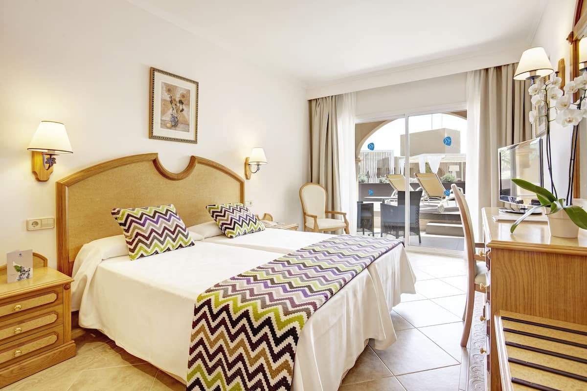 A hotel room with a bed, bedside tables, a desk, and a chair.