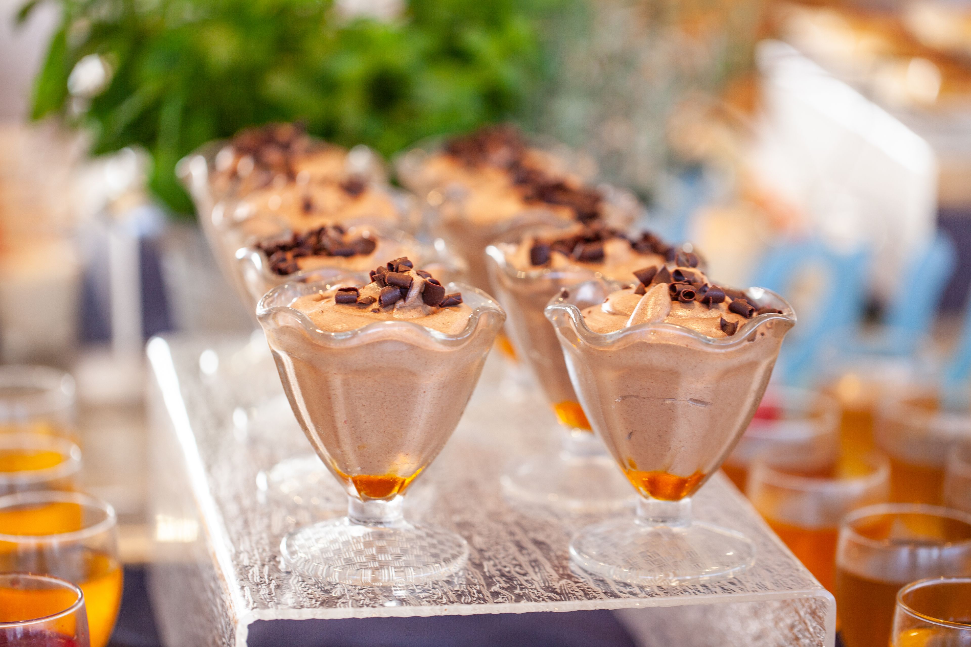 A dessert table with chocolate mousse in glass cups topped with chocolate shavings.