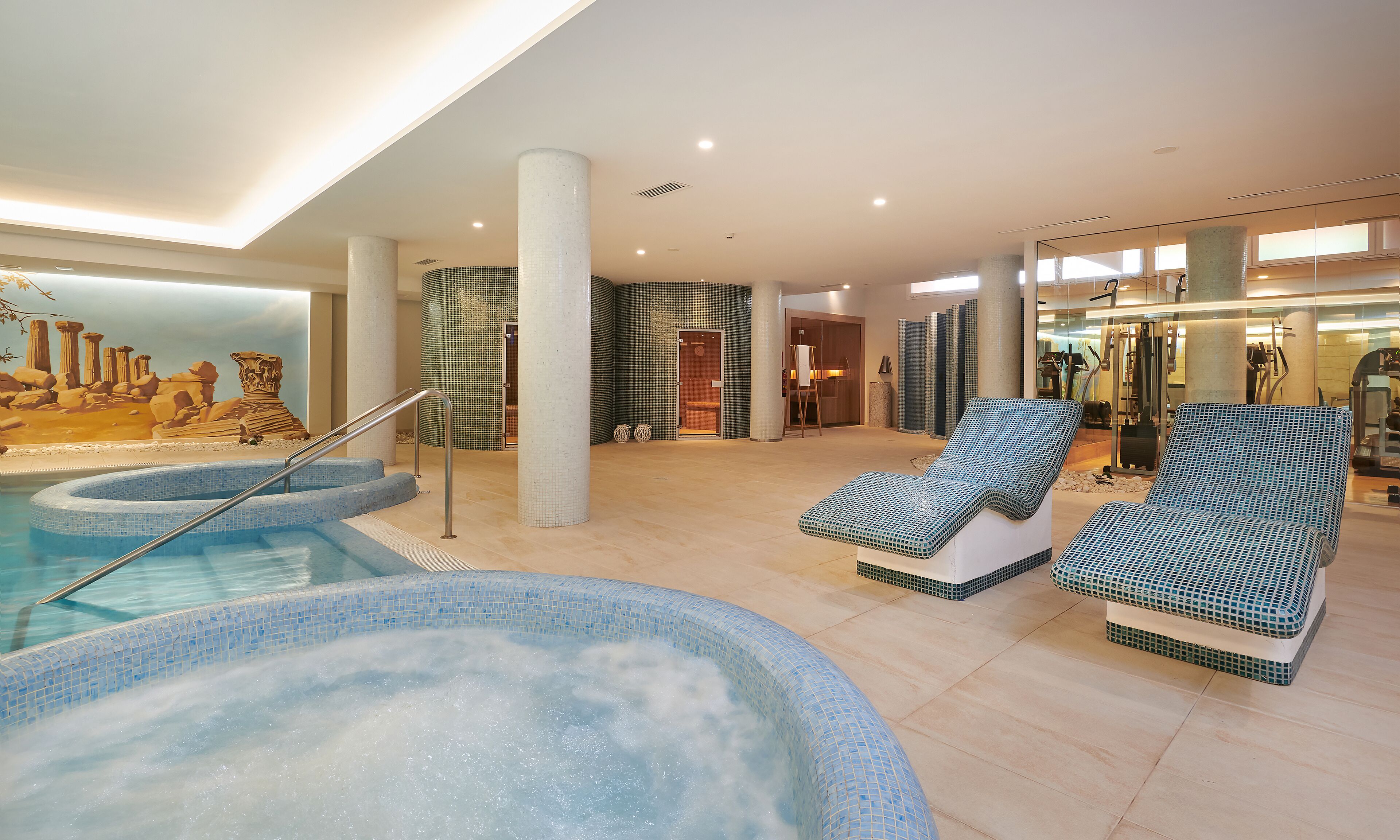 A spa area with a hot tub, lounge chairs, and a mural.