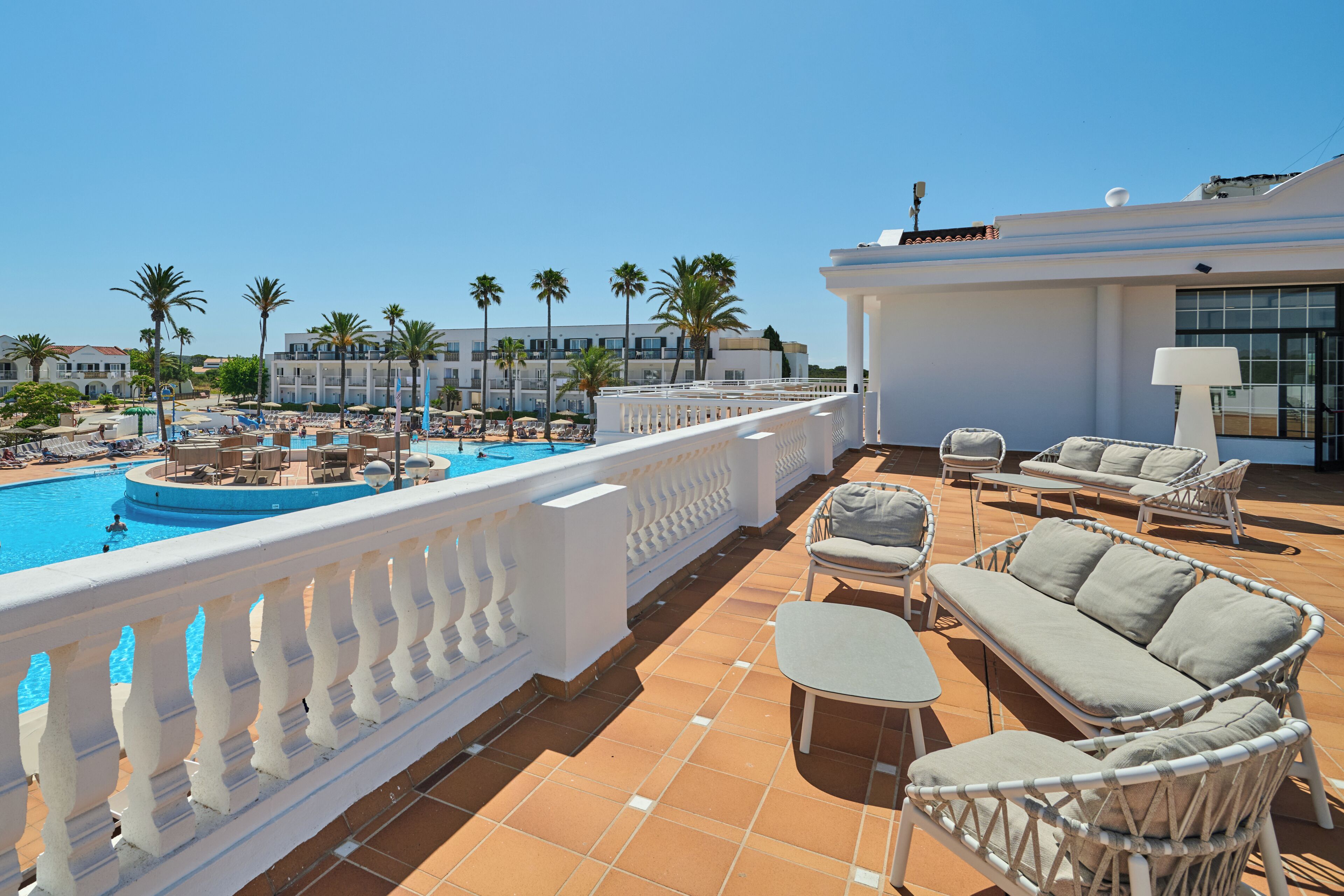 A rooftop pool area with lounge chairs and a view of the pool.