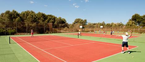 Una cancha de tenis al aire libre con varios jugadores.