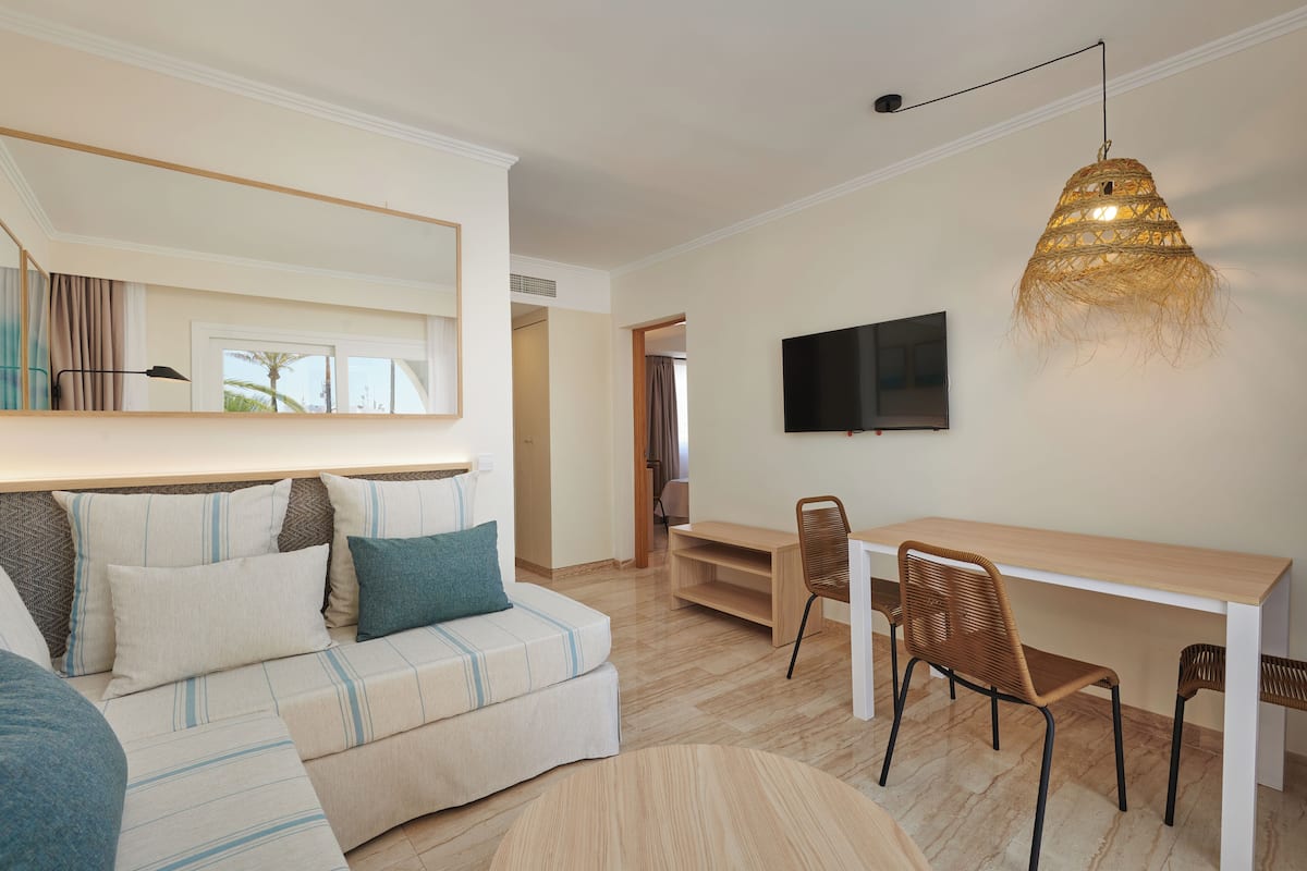Uma sala de estar moderna com um sofá, cadeiras, uma mesa de jantar e uma televisão.