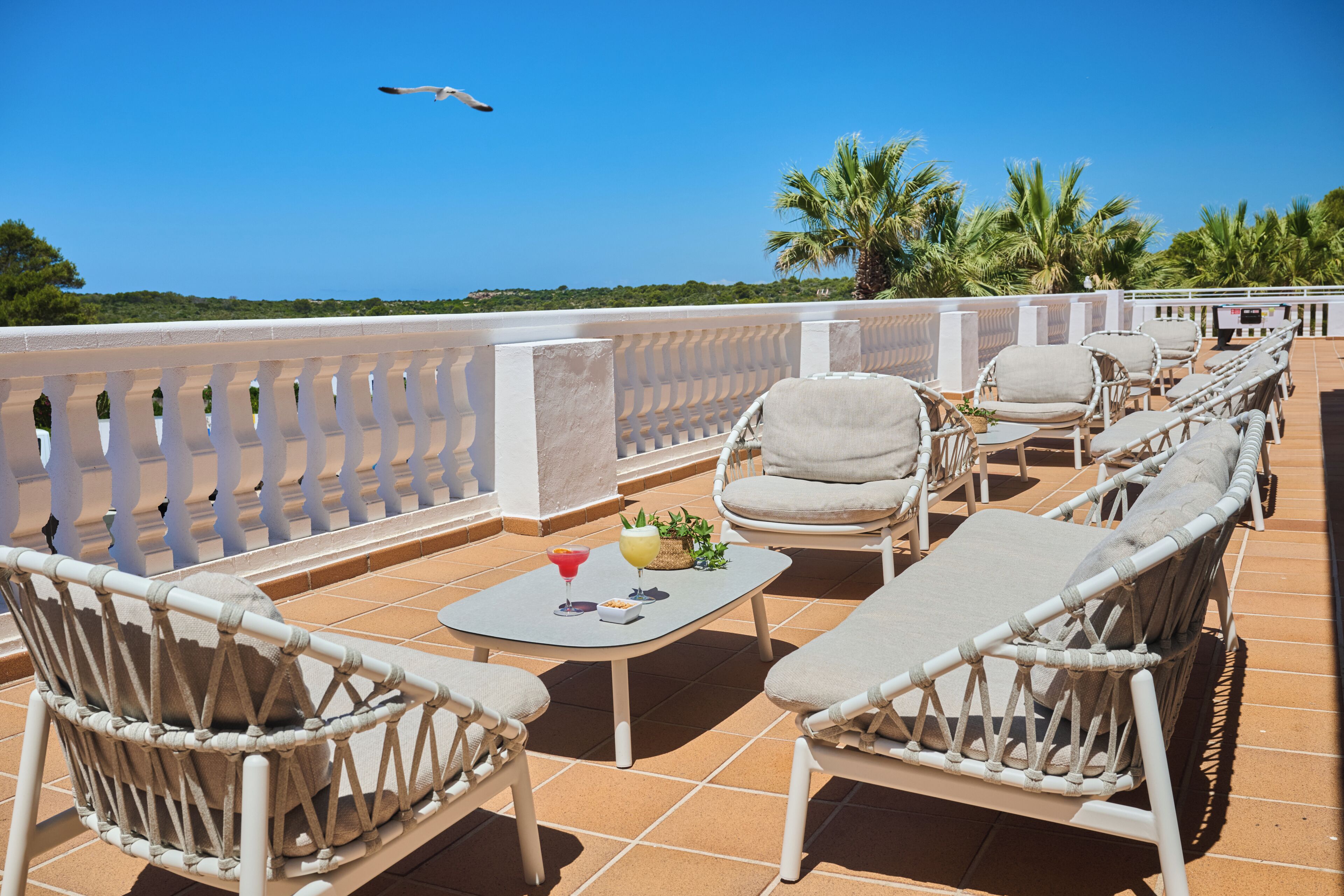 Una terrazza con mobili in vimini, un tavolo con bevande e vista sul mare.
