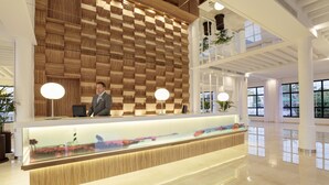 Una moderna recepción con un muro de paneles de madera, un acuario de vidrio y un suelo pulido.