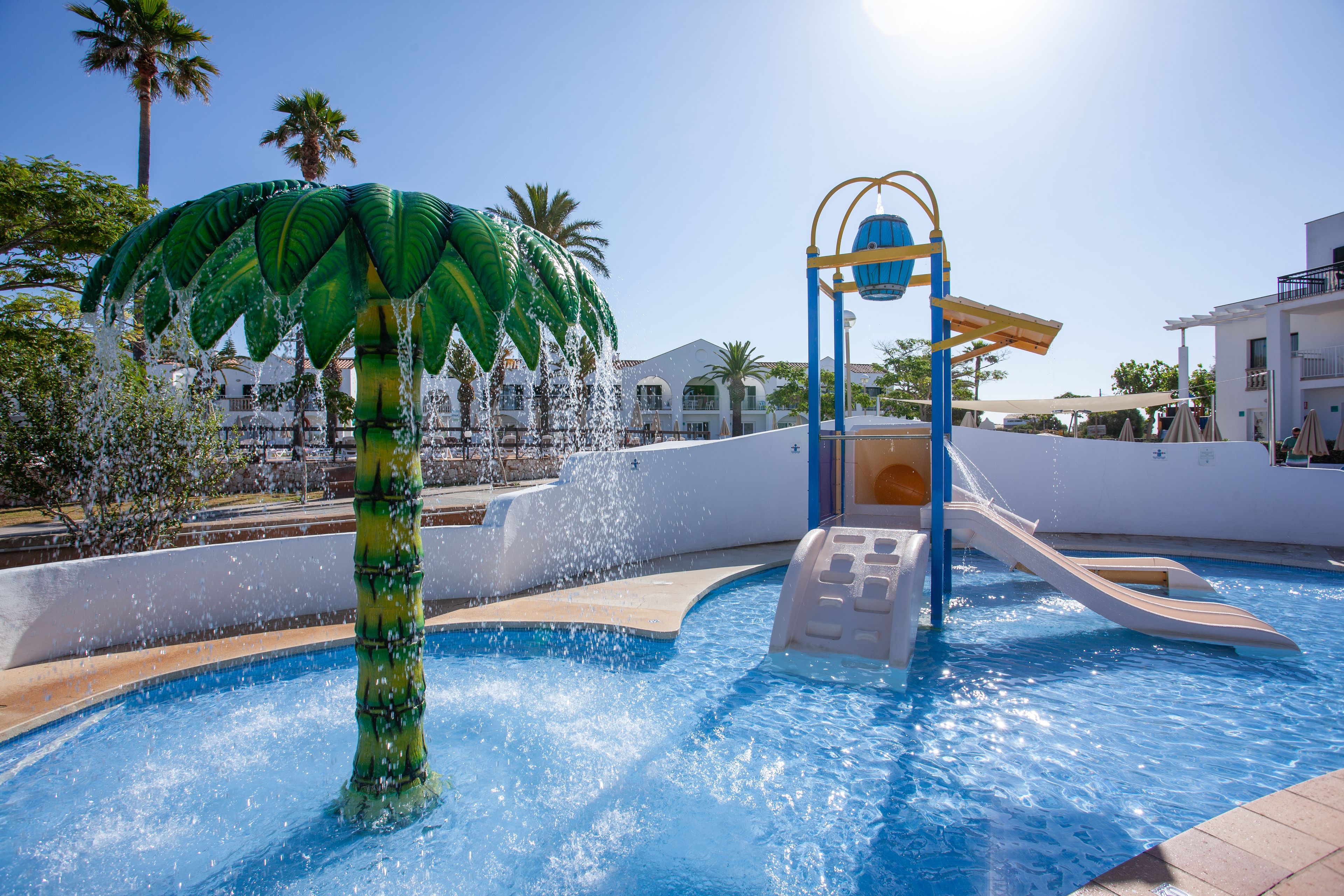 A swimming pool with a water slide and a palm tree decoration.
