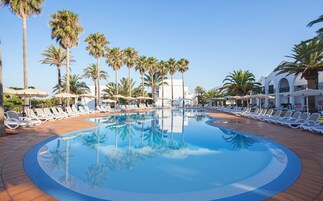 Una piscina al aire libre, sombrillas, sillones reclinables de piscina