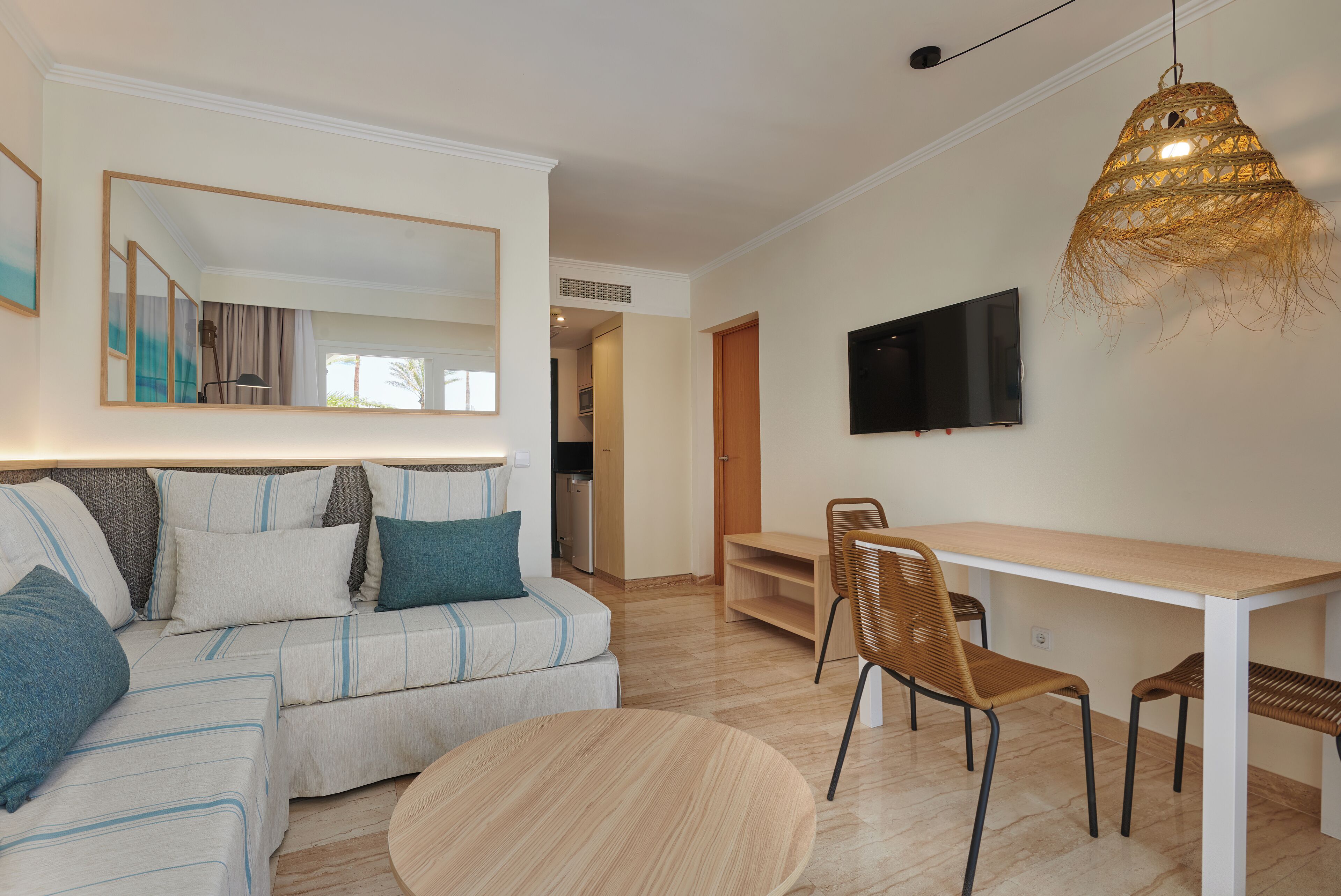 Un salon moderne avec un canapé, une table ronde et un téléviseur fixé au mur.