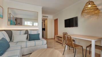 Una sala de estar moderna con un sofá, una mesa redonda y un televisor montado en la pared.