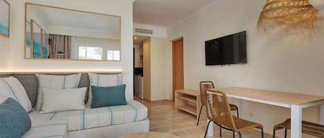 Ein modernes Wohnzimmer mit einer Couch, einem runden Tisch und einem an der Wand befestigten Fernseher.