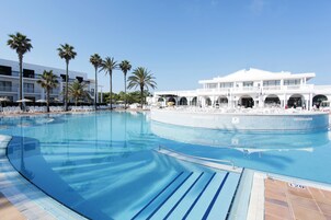 Una piscina al aire libre, sombrillas, sillones reclinables de piscina