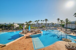 Una piscina al aire libre, sombrillas, tumbonas