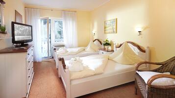 A hotel room with two beds, a television, a dresser, a chair, and a window with curtains.