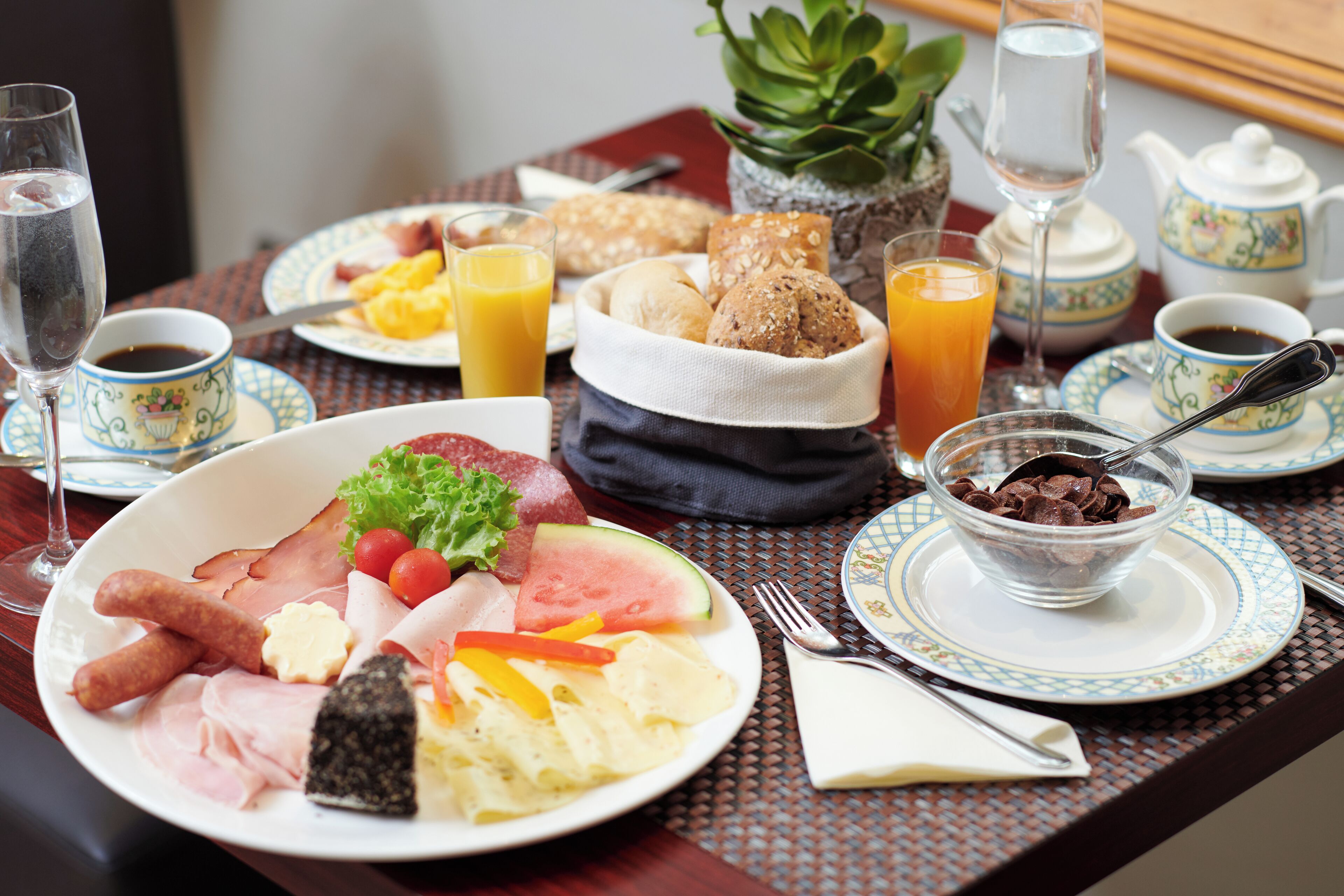 Une table de petit-déjeuner avec divers aliments, des boissons et une théière.