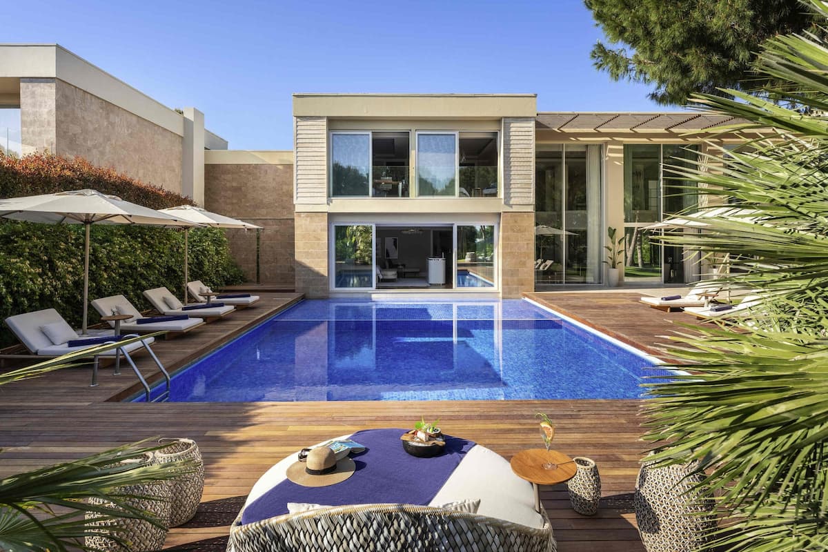 A modern house with a swimming pool, lounge chairs, and a dining area with outdoor furniture.