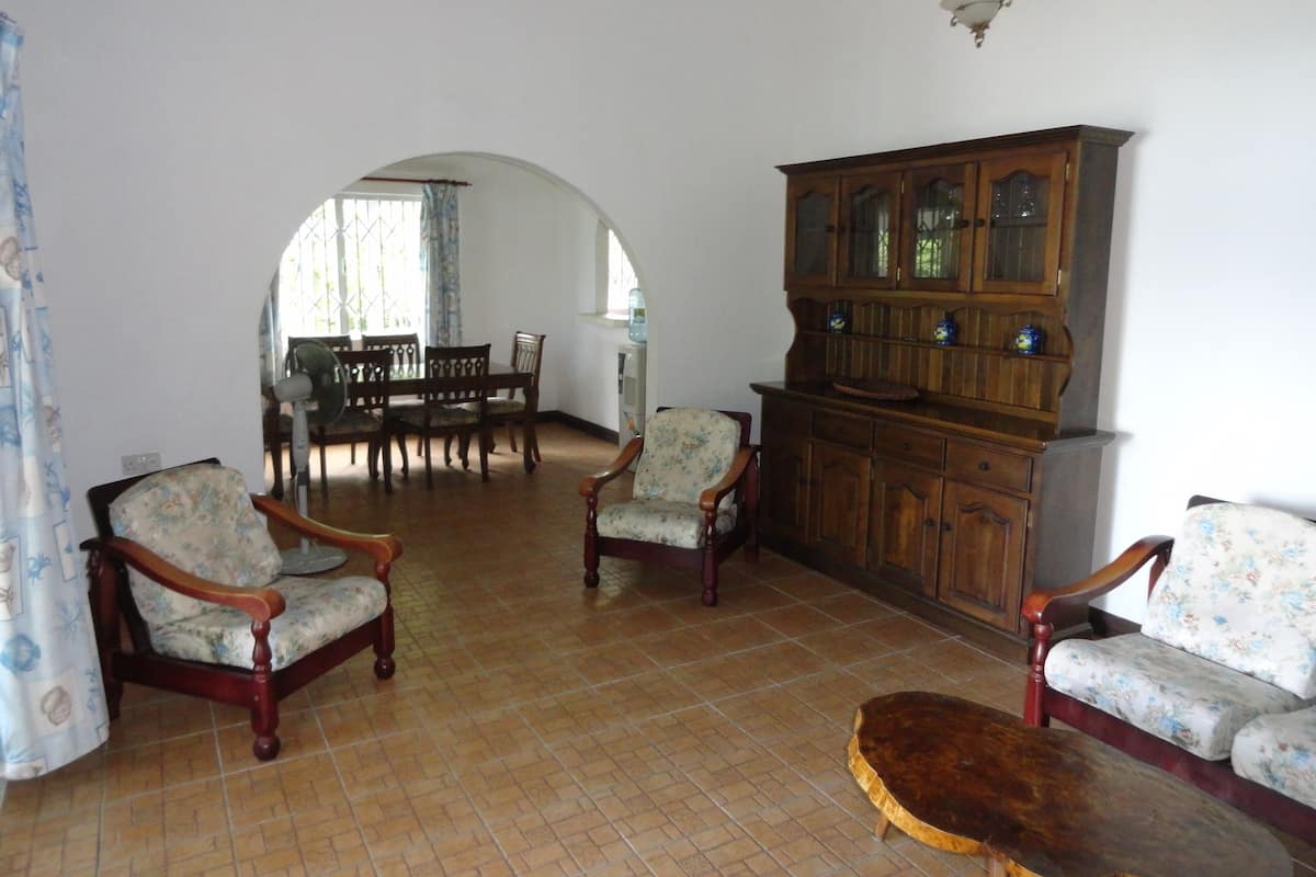 A spacious living room with a tiled floor, wooden furniture, and a large cabinet.
