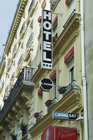 Une enseigne d’hôtel avec les mots « HÔTEL » et « CANAL SAT » sur la façade d’un immeuble.