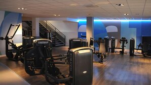 Un gimnasio con diferentes máquinas de ejercicio, una escalera y un diseño de pared azul.