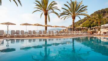 Alberca al aire libre, sombrillas en la alberca y camastros