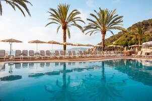 Una piscina al aire libre, sombrillas, sillones reclinables de piscina